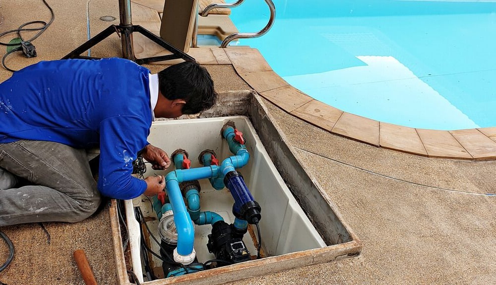 Homme qui entretien et réparer la pompe de filtration d'une piscine
